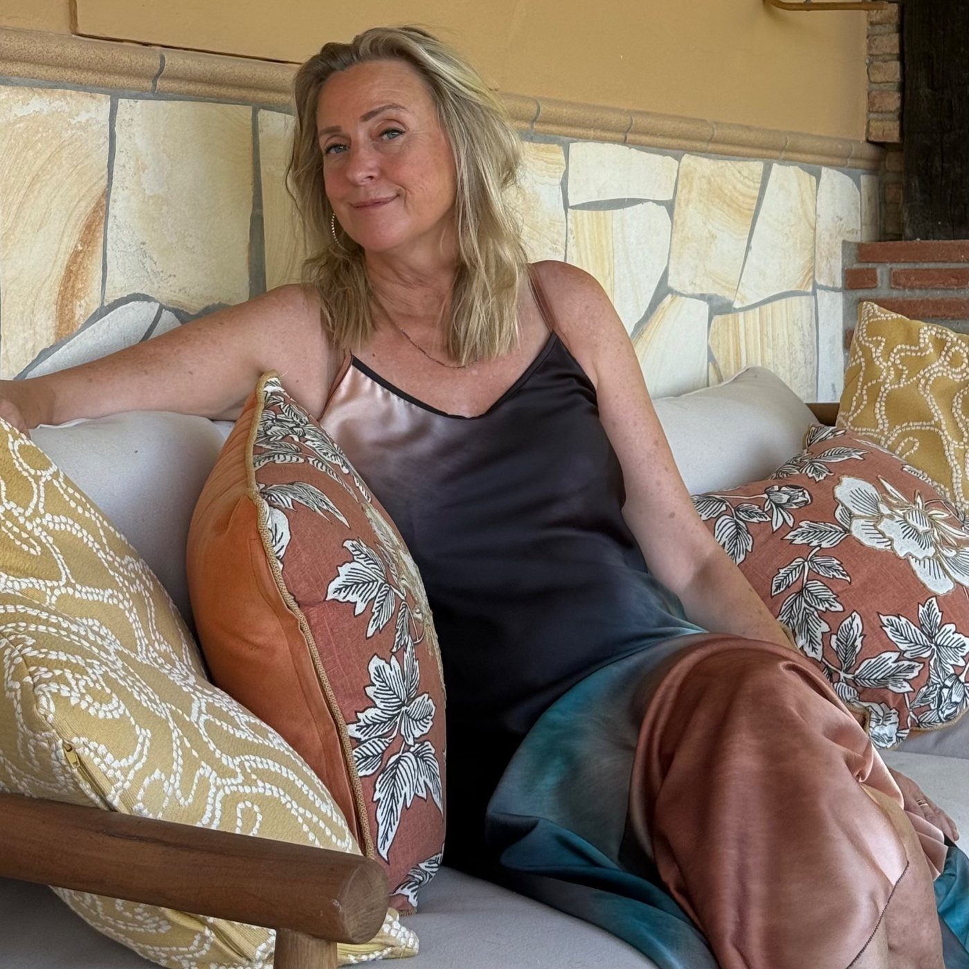 Sara Lee relaxing on an outdoor sofa on her terrace, smiling at the camera.